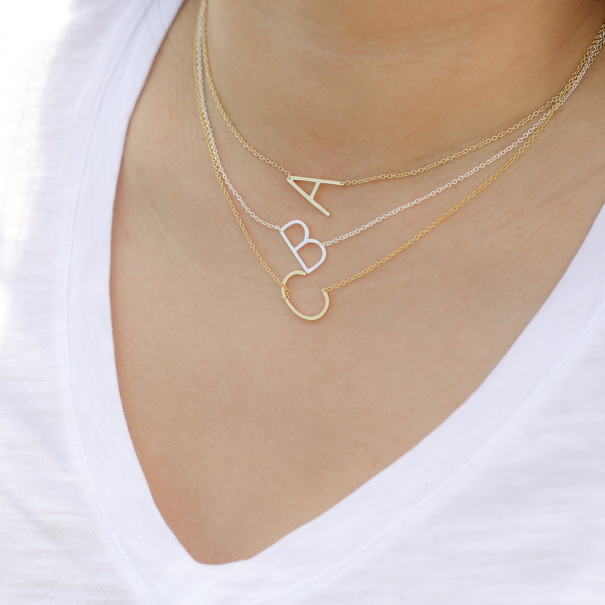 Layering Alexandra Marks sideways initial necklaces in silver and gold