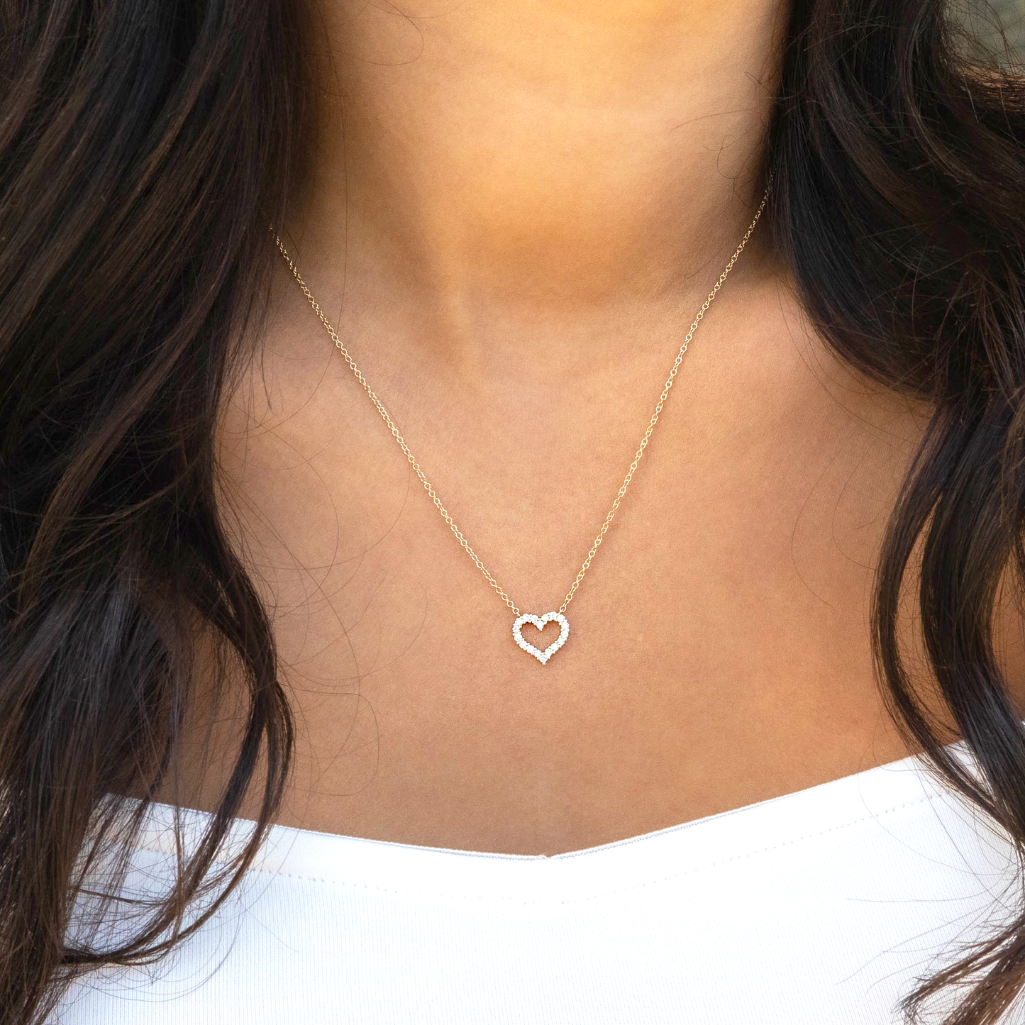 Necklace with a heart-shaped pendant worn by a person with dark hair and a white top.