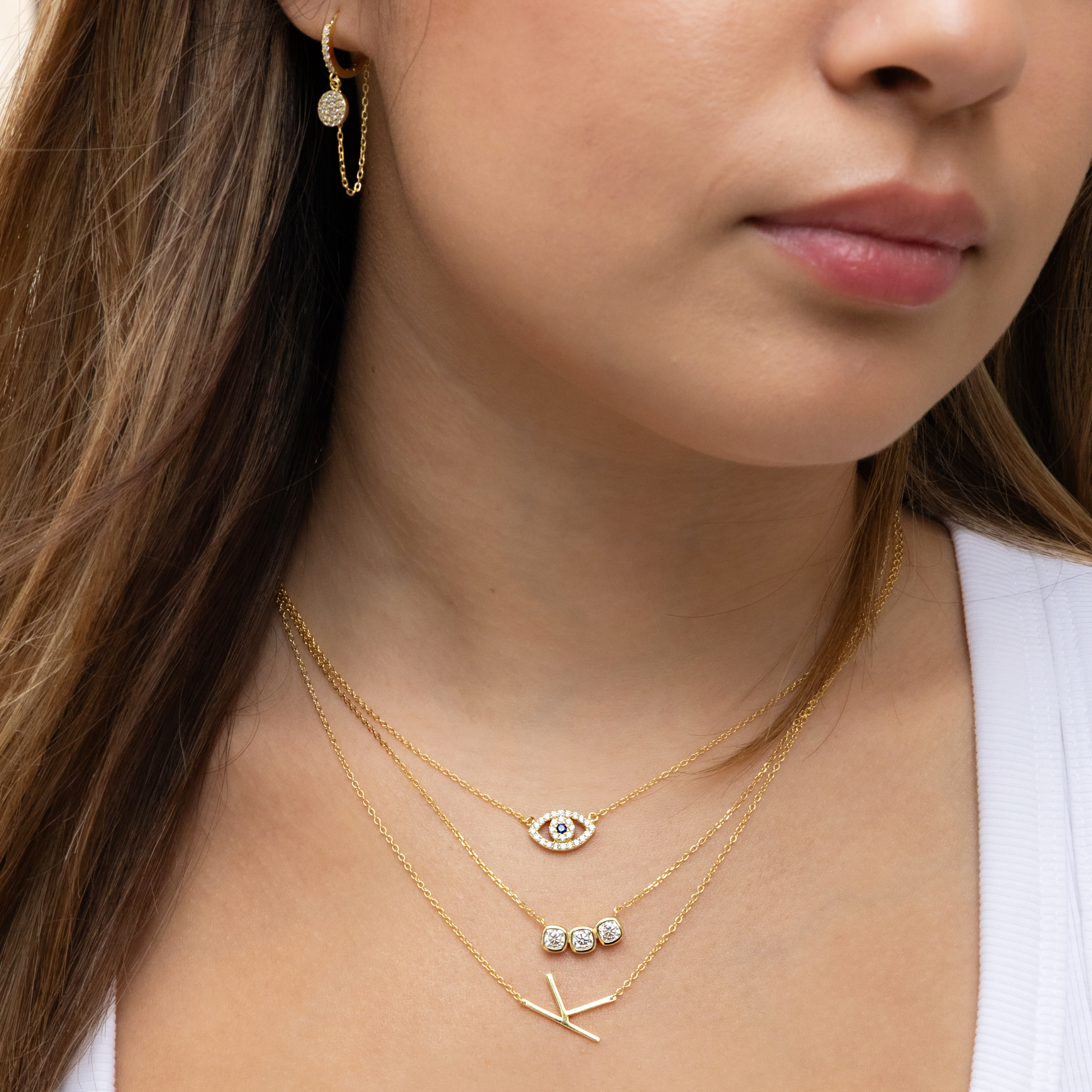 Gold Necklace Stack with our best selling sideways initial necklace, evil eye necklace and triple bezel cz bar necklace. 
