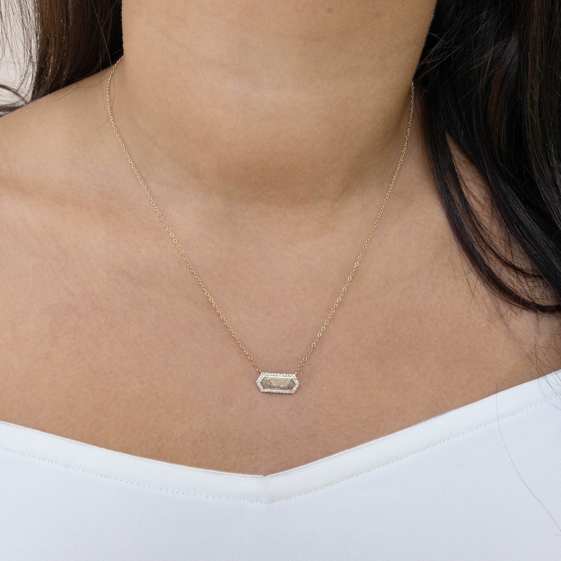 Hexagon gold bar necklace on a person