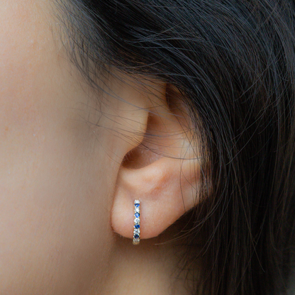 Sapphire and diamond huggie hoop earrings in gold. 