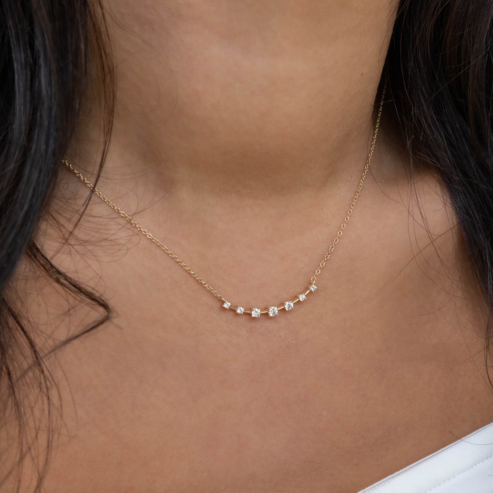 Gold necklace with small diamonds on a person's neck