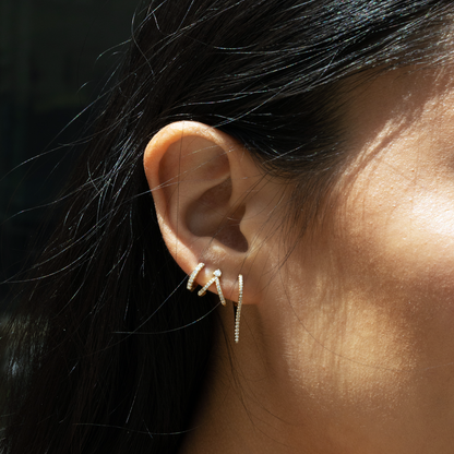 Dainty diamond earring stack in 14kt yellow gold featuring a bar drop hoop, tiny huggie earring and a spilt v stud. 