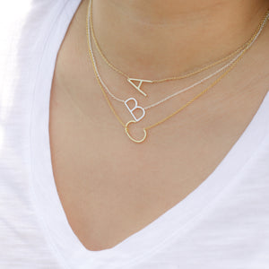 Layering Alexandra Marks sideways initial necklaces in silver and gold