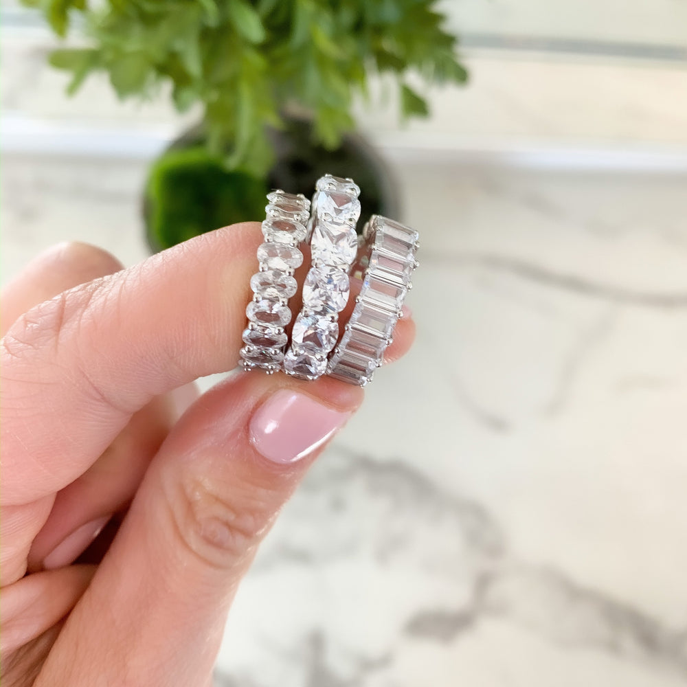 Alexandra Marks holding 3 of her favorite cz eternity bands in silver