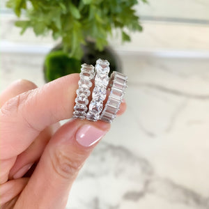 
            
                Load image into Gallery viewer, Alexandra Marks holding an oval eternity band, a cushion cut eternity band and the baguette eternity band in silver
            
        