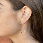 Model wearing the thin gold criss cross hoop earrings